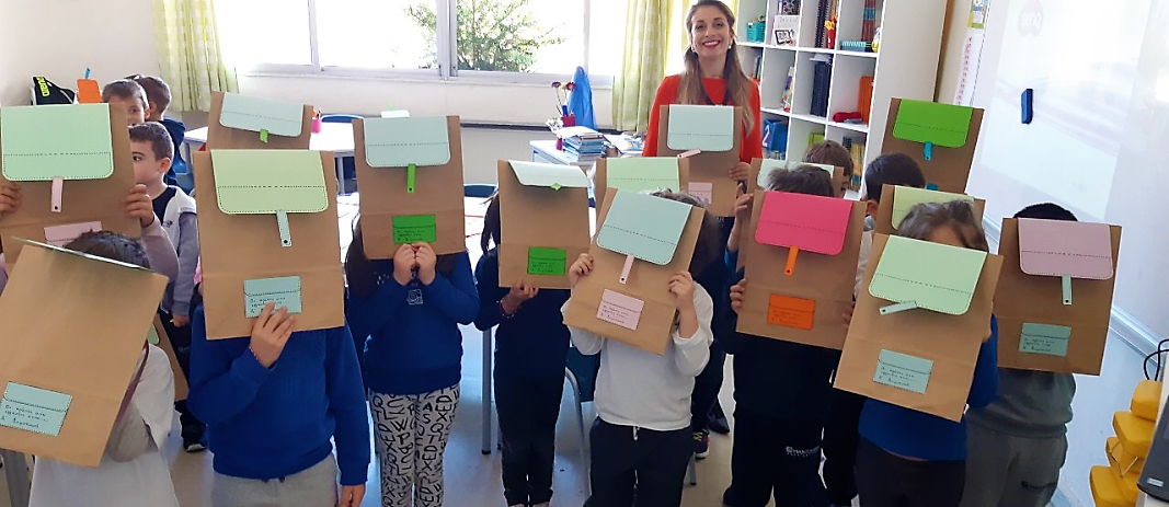 Students of the Kindergarten of mandoulides schools with their faces covered by paper bags and with their teacher on the back