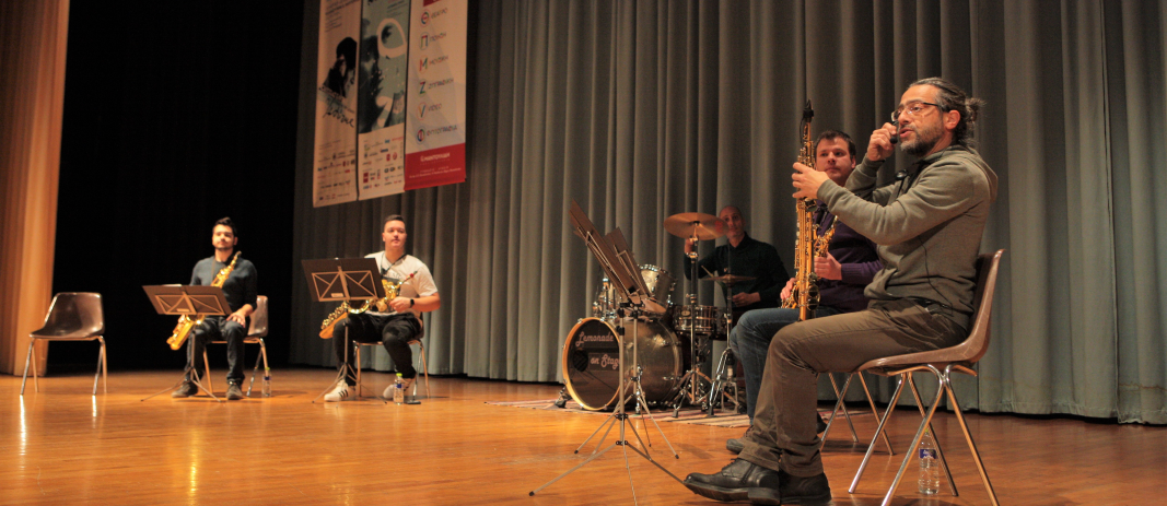 4 άτομα με μουσικά όργανα πάνω σε μια σκηνή να παίζω μουσική