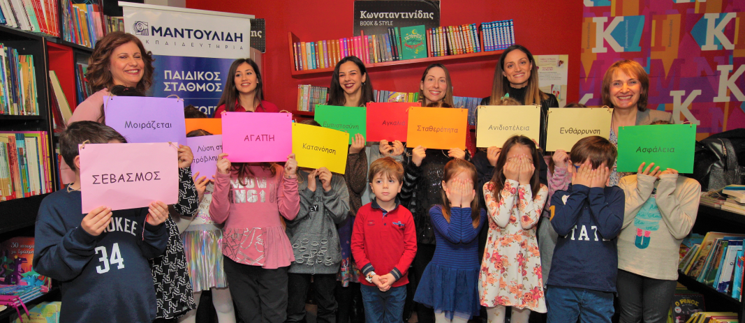 Students of the 3rd grade of mandoulides schools with colored words covering their facesa