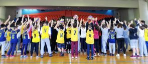 Students of the 6th and 7th grade of mandoulides schools looking at the crowd with their hands up, after the basketball game between them