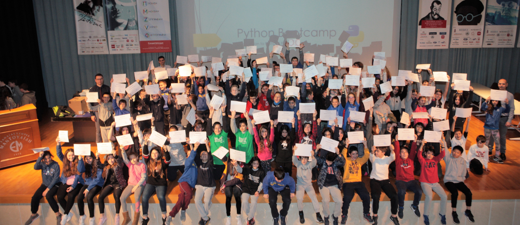 All the participating students of MAndoulides Schools on the stage holding their certificates up high