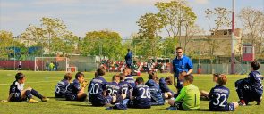 Στην Εκδρομή Ακαδημίας Ποδοσφαίρου στην Αθήνα, οι μικροί ποδοσφαιριστές των εκπαιδευτηρίων καθισμένοι στο γρασίδι του γηπέδου ποδοσφαίρου ακούν τον προπονητή τους