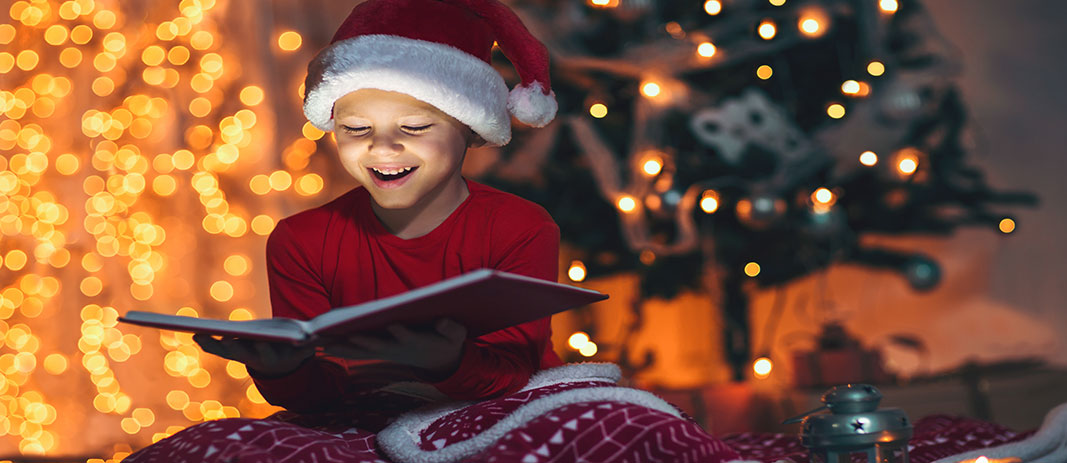 Boy Reads Book In Front Of Christmas Tree