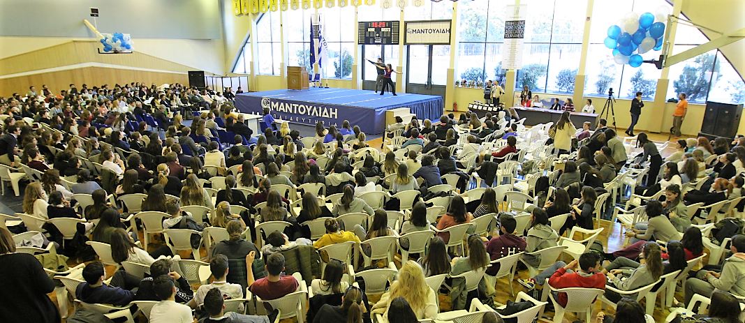 To αθλητικό κέντρο των εκπαιδευτηρίων γεμάτο με θεατές που παρακολουθούν στη σκηνή ένα ντουέτο