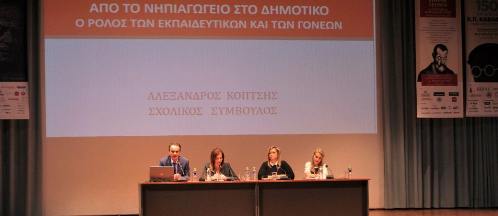 Mr koptsis, mrs hasioti, mrs tutuntzi and mrs papadopoulou, sit on a wooden table placed on the theatre scene on mandoulides schools and talk to the crowd